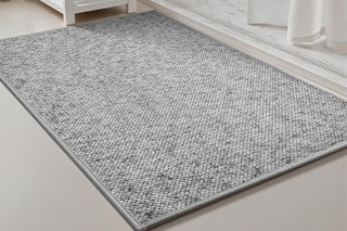A heather grey low-pile bathmat sits in front of a white marble shower