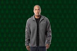 man wearing a gray zip up hoodie with a christmas tree background