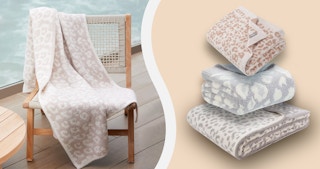 A Barefoot Dreams blanket draped over a wooden chair next to a stack of dupes.