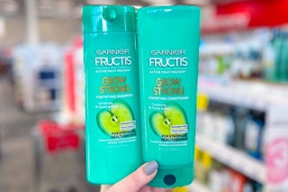 hand holding two bottles of garnier fructis shampoo conditioner in a store aisle
