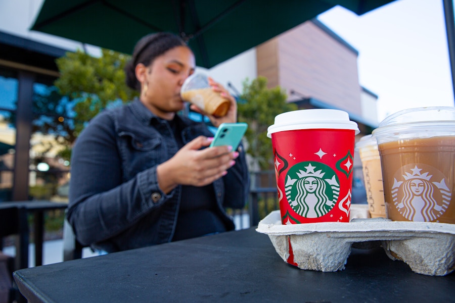 someone sipping a coffee and looking at their phone at starbucks