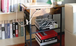 a wooden table in the sun by a bookshelf