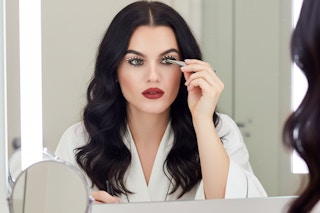a woman putting on kiss lashes