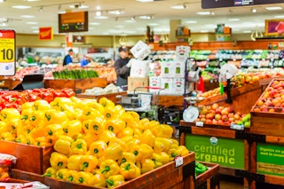 Customers shopping and employees restocking the produce section in a King Soopers store.
