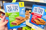 person holding a box of nutri-grain bars by the shelf