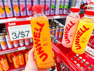 hand holding an unwell drink in front of target cart and signage