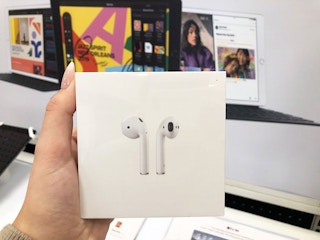 a hand holding a box with Apple AirPods