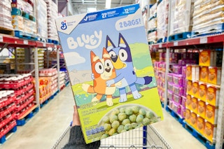 person holding a large box of bluey cereal in an aisle