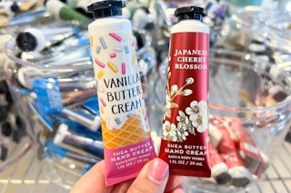 a person holding two mini bath and body works hand cream