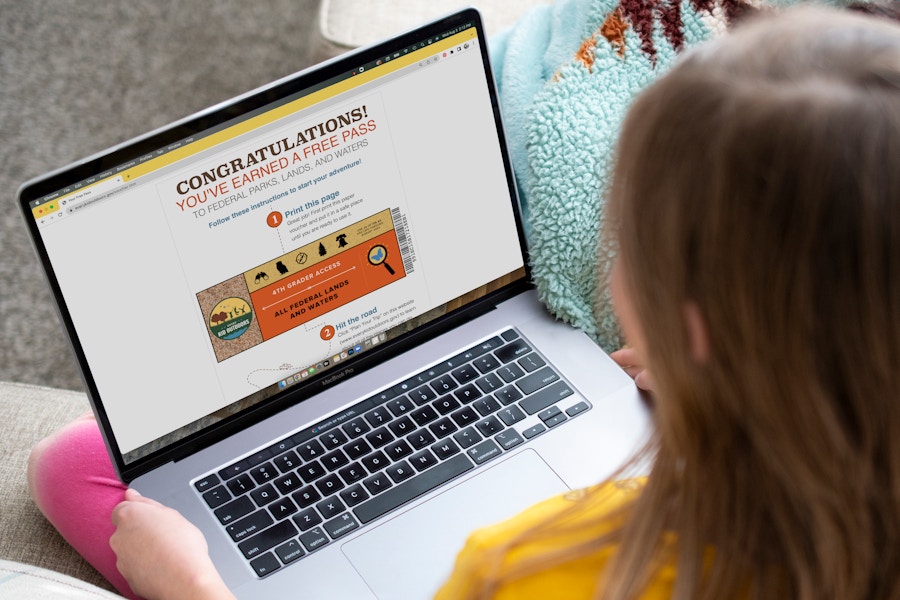 A child on a computer looking at an Every Kid Outdoors national park pass.