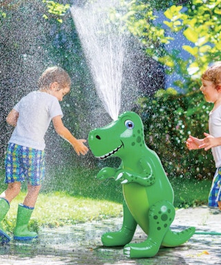 little kids playing outside running around an inflatable dinosaur sprinler