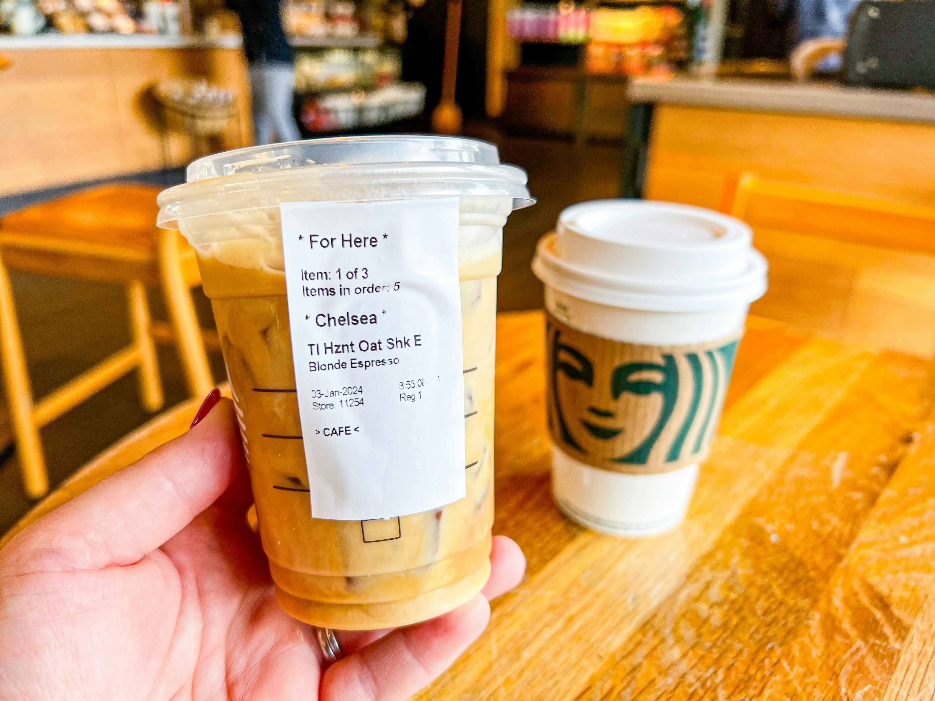 starbucks winter menu drink being held with another drink on table 