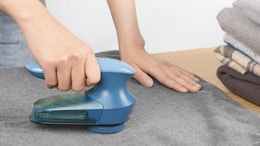 a hand using a lint shaver on a sweater