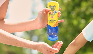hand squeezing a yellow bottle of banana boat sunscreen