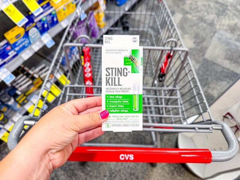person holding sting kill pain reliever over a cvs cart
