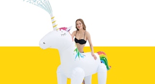 A woman standing next to an inflatable unicorn sprinkler
