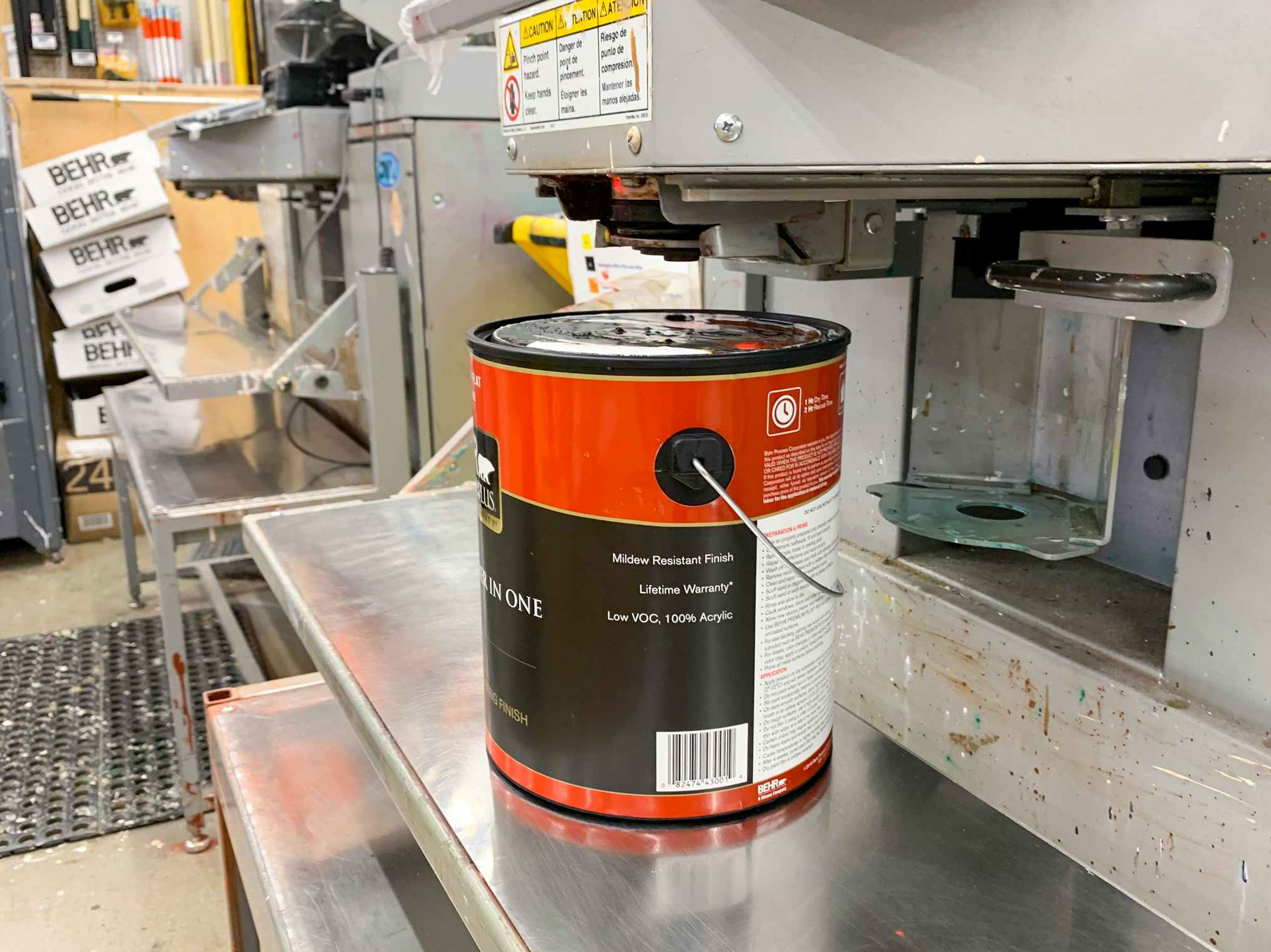 An open can of paint sitting below the machine used for tinting paint at Home Depot