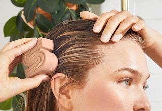 a woman washing her hair with a S-shaped shampoo bar