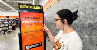 a person looking at a spirit halloween hiring sign