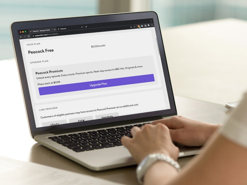 A person using a laptop displaying their Peacock free subscription plan.