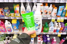 person holding raw sugar and dove body washes in front of the shelf