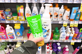 person holding raw sugar and dove body washes in front of the shelf