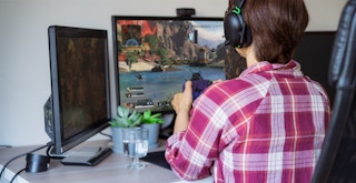 A person sitting at a computer, playing Apex online with friends