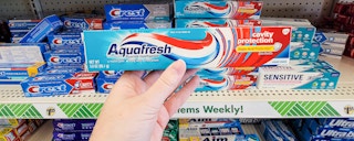 hand holding a tube of aquafresh toothpaste