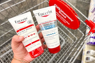 hand holding two eucerin eczema relief lotions over a shopping cart