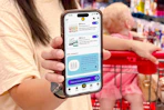 person holding a smartphone displaying KCL App Coupons