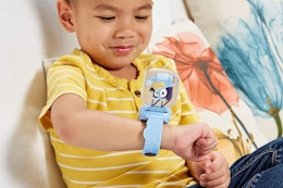 a boy playing with a bluey watch