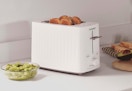 a beige toaster on a counter with toast in it