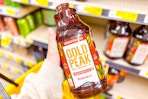 hand holding a bottle of gold peak tea