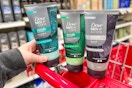 hand holding a blue and gray bottle of Dove Men+Care scrub in front of two other bottles
