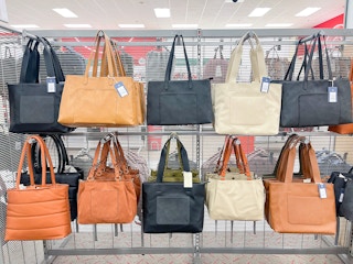A variety of purses hanging from a store rack.