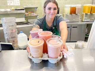 a jamba juice employee giving a bunch of juices
