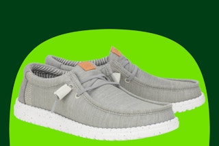 A gray pair of men's Hey Dude Shoes on a light and dark green background. 