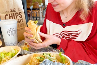 a woman eating chipotle and wearing a hockey jersey