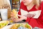 a woman eating chipotle and wearing a hockey jersey