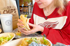 a woman eating chipotle and wearing a hockey jersey