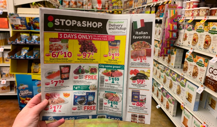 Hand holding up Stop & Shop weekly ad inside of store