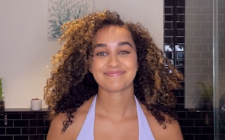 A woman with curly hair smiling after using Garnier hair products.