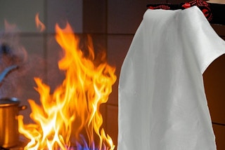 an adult using a fire blanket on a fire