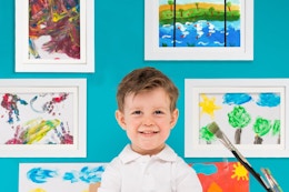 kid standing in front of framed paintings