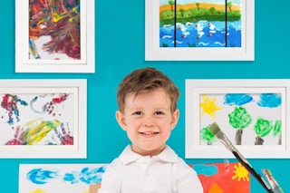 kid standing in front of framed paintings