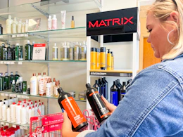 a women holding jumbo shampoos in front of the shampoo and conditioner display