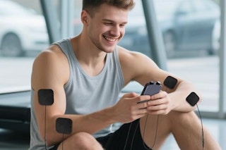 Man using the Uthlusty TENS Unit Muscle Stimulator at a gym.