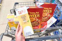 hand holding walgreens trash bags above shopping cart 