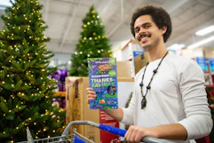 a person stand by a cart holding a sams club black friday book