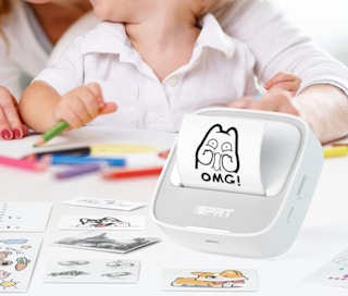 a sticker printer on a table with stickers next to a mom and kid